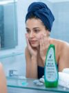 GLAMURNY Blue Herbal Face Wash 100ml placed on bathroom counter while a woman gently washes her face, highlighting herbal skincare, deep cleansing and smooth hydrated skin.
